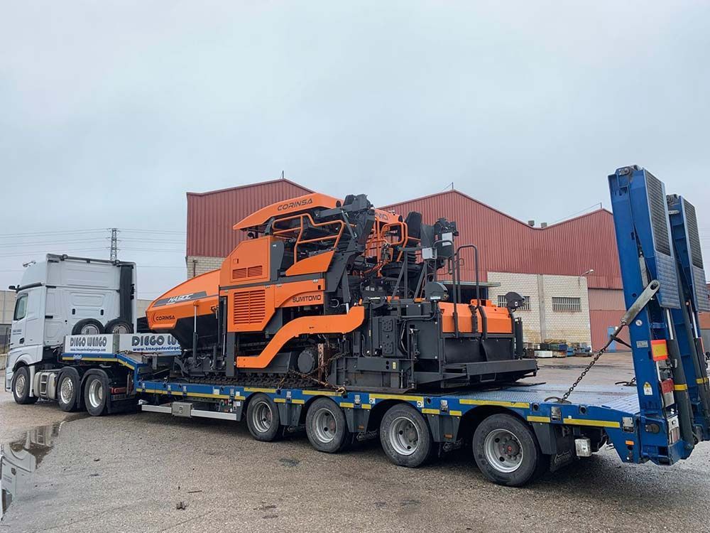 Un camión semirremolque transporta una gran máquina naranja en un remolque.