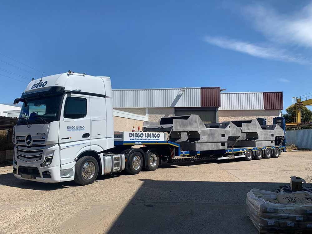 Un camión semirremolque blanco está estacionado frente a un edificio.