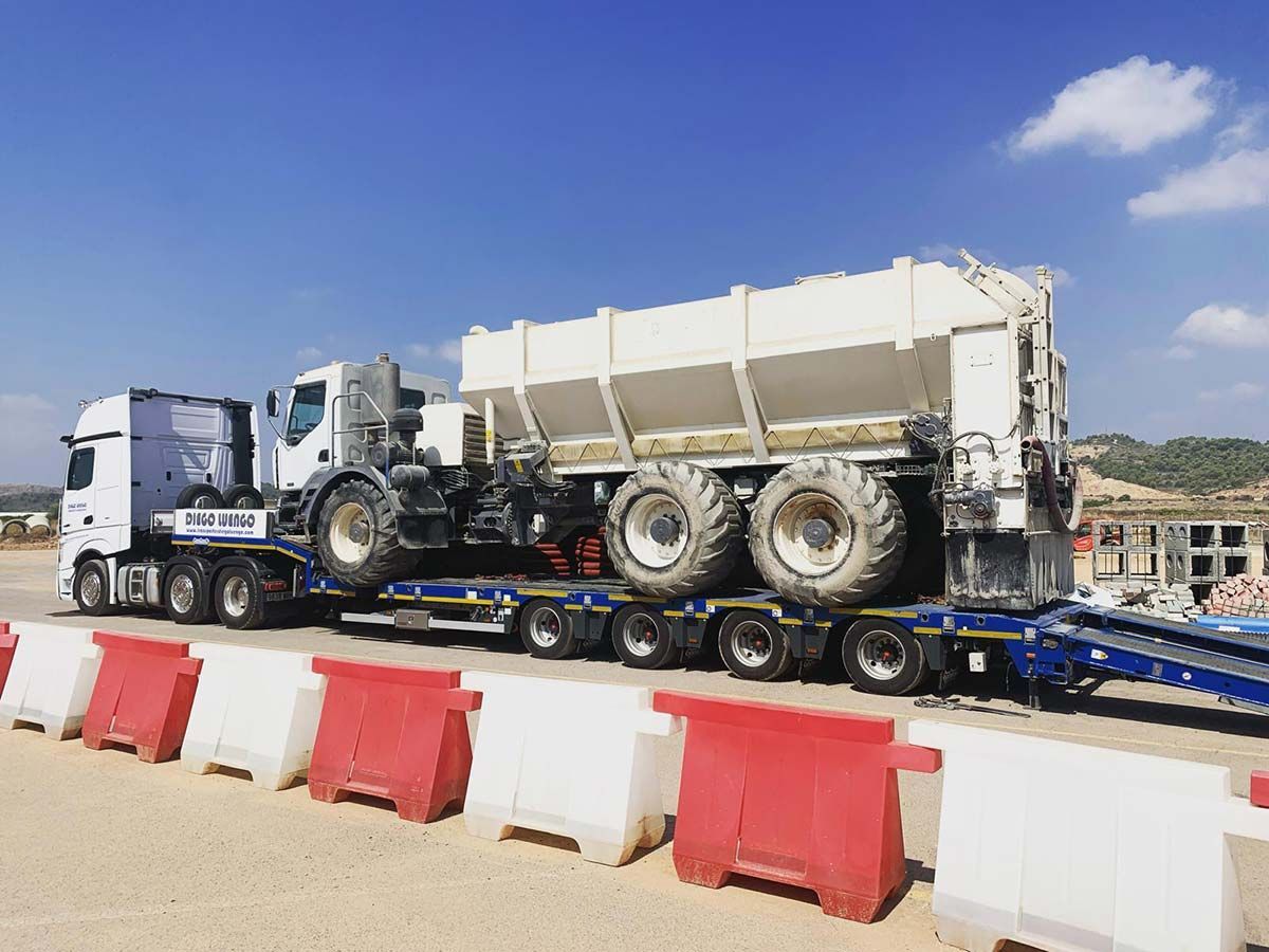Un camión semirremolque transporta un tractor en un remolque.