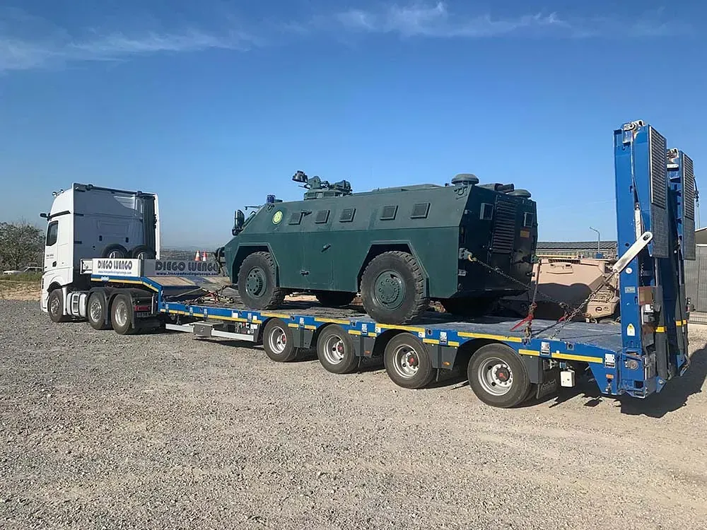 Un vehículo militar está siendo transportado en un remolque.