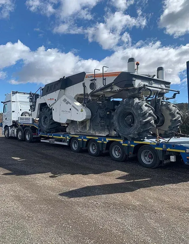 Un camión transporta una máquina grande en un remolque.