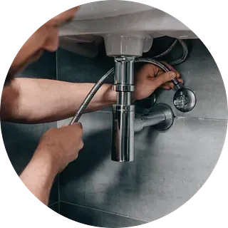 Una persona está conectando una manguera de agua flexible debajo de un fregadero.