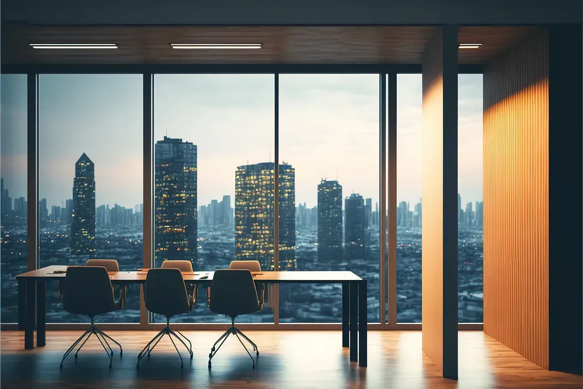 Sala de reuniones con vista al horizonte de la ciudad al atardecer. Mesa y sillas, paneles de madera y amplios ventanales.