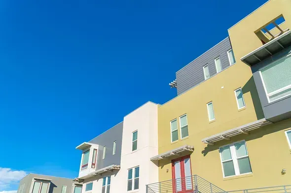 Hilera de casas adosadas coloridas contra un cielo azul brillante.