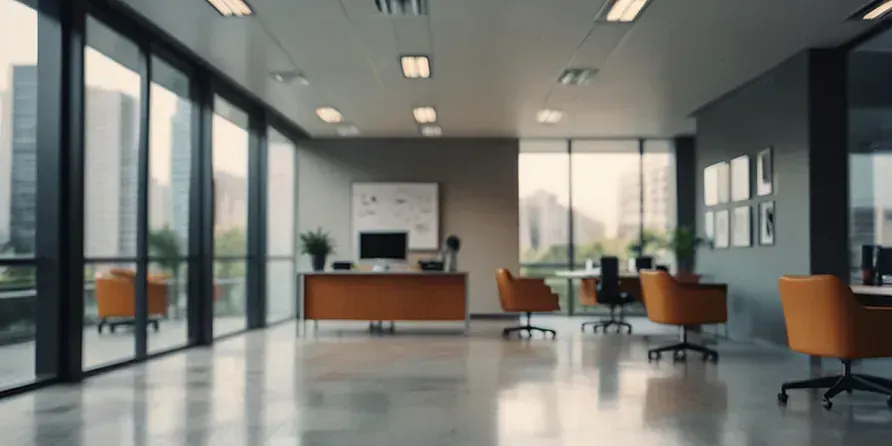 Interior de oficina moderno con grandes ventanales, escritorios y sillas naranjas.