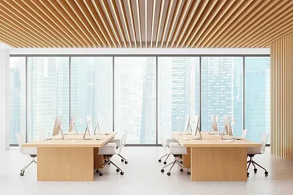 Espacio de oficina moderno con detalles en madera clara, paredes de cristal y vistas a la ciudad. Escritorios y sillas dispuestos para facilitar la colaboración.