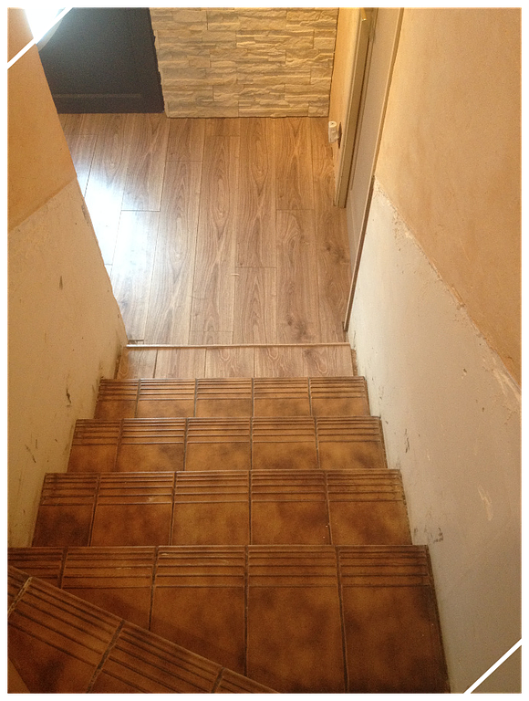 Escalier tournant avec carrelage ancien, vue sur un couloir