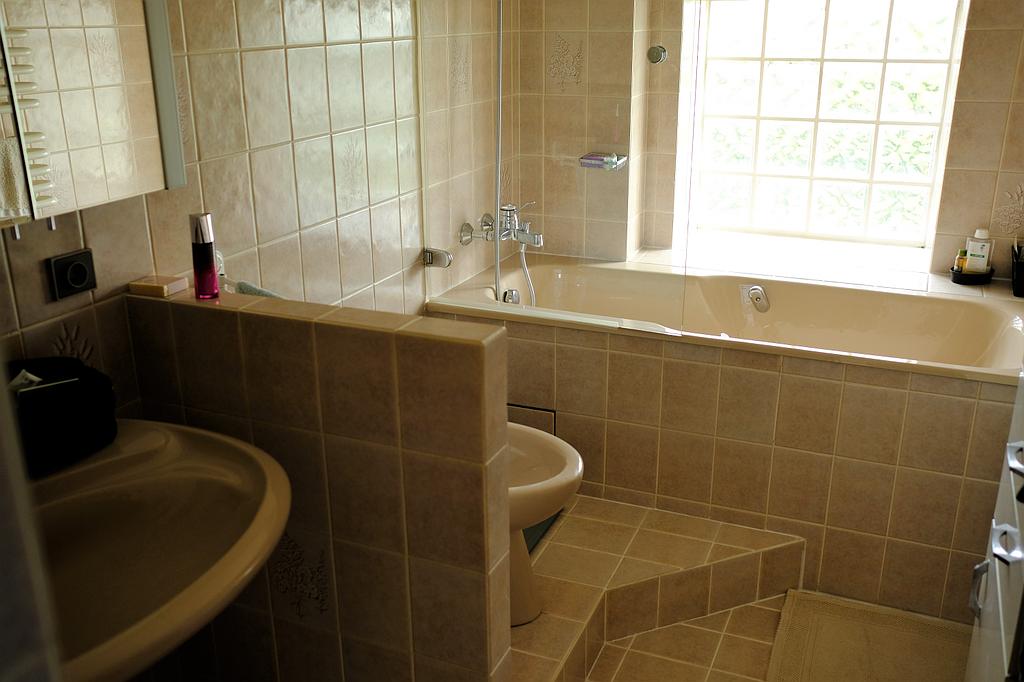 Salle de bains avant travaux : carrelage beige et baignoire encastrée 