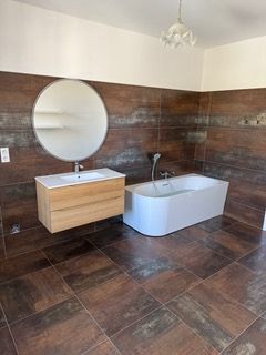 Après les travaux avec un lavabo en bois et d'une baignoir moderne