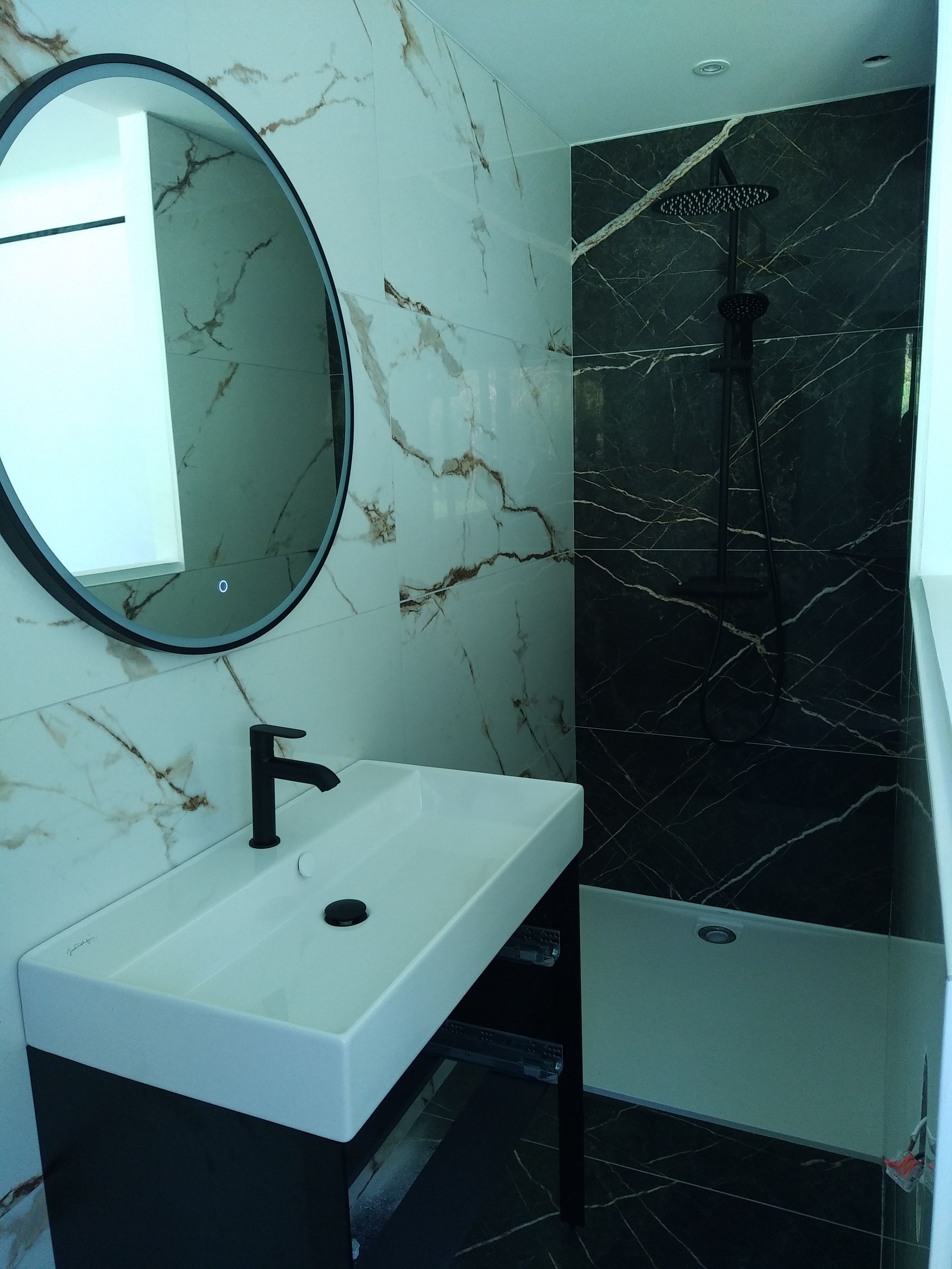 Salle de bains avec design moderne, marbre noir et blanc. Robinetterie noire et vasque suspendue