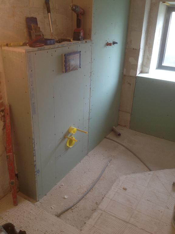 Installation de plaques hydrofuges et de plomberie avant la pose du carrelage