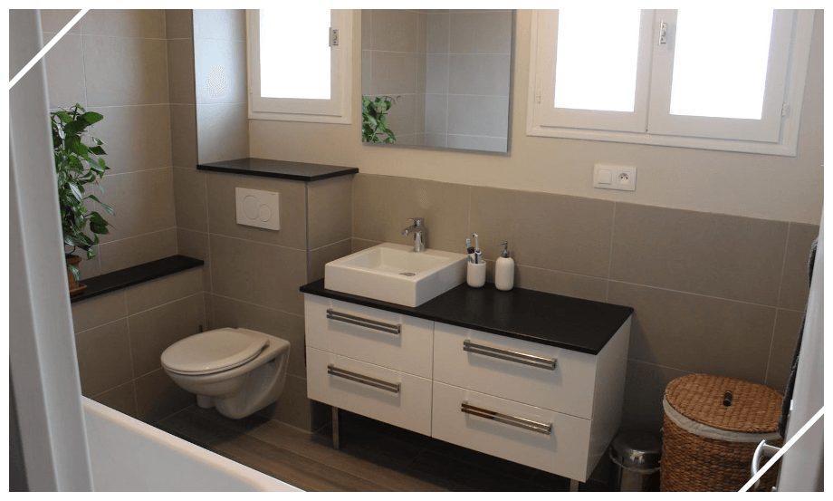 Salle de bains avec toilettes, meuble avec vasque posée et faïence grise