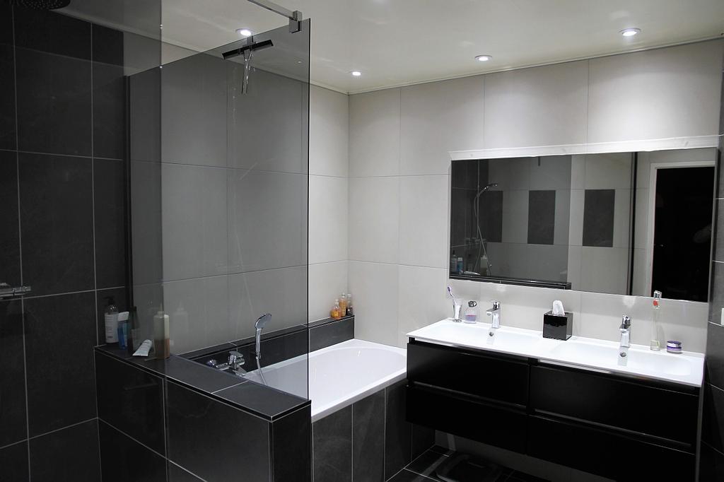 Salle de bains avec baignoire et douche, meuble double vasque, carrelage noir et blanc
