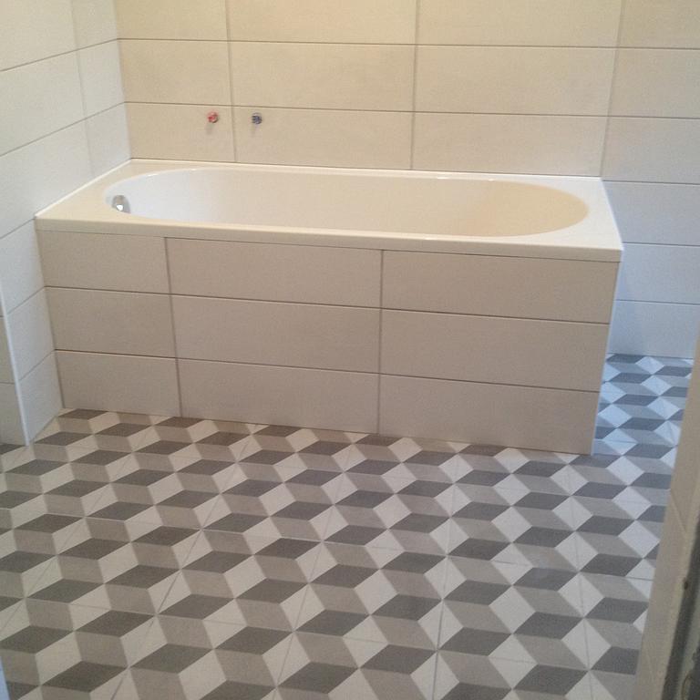 Baignoire avec tablier carrelé et carrelage au sol aux motifs géométriques