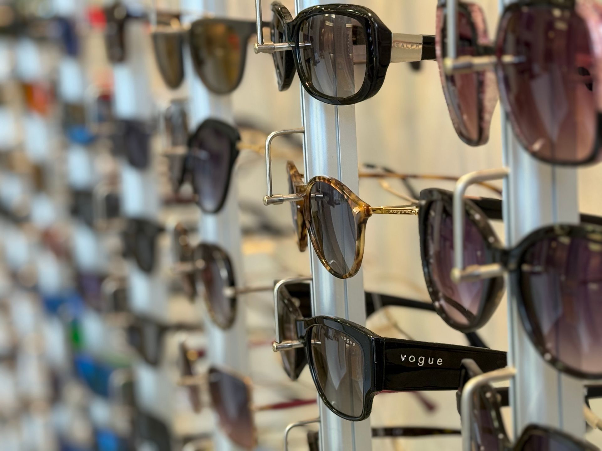Lunettes de soleil exposées dans un magasin, avec des montures de styles et de couleurs variés.