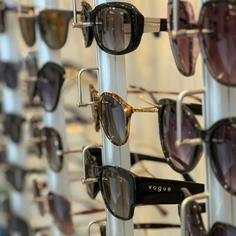 Lunettes de soleil présentées sur un présentoir. Différents styles et couleurs de montures sont visibles.
