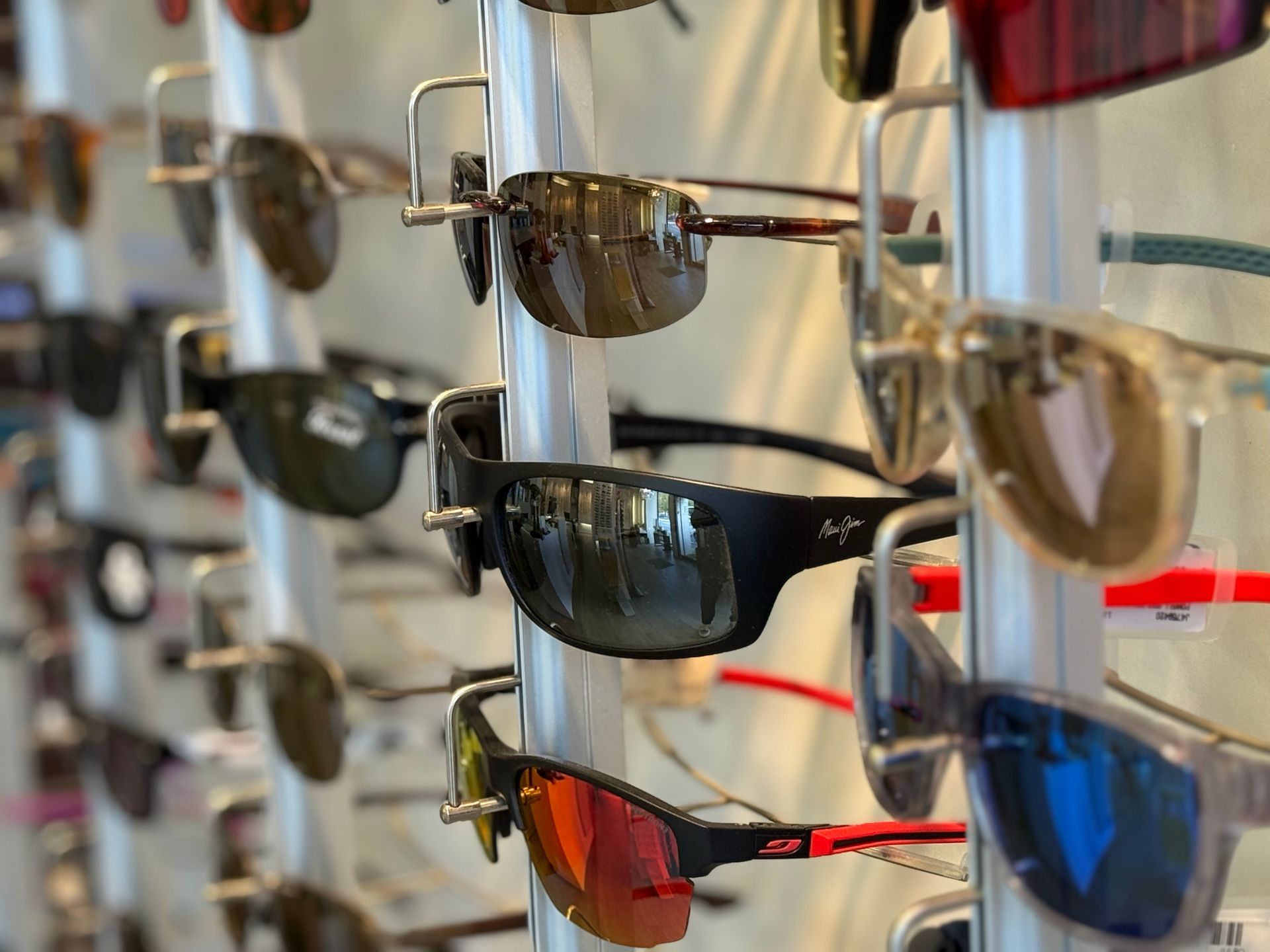 Lunettes de soleil présentées sur un présentoir en magasin ; différents styles et couleurs de verres sont visibles.