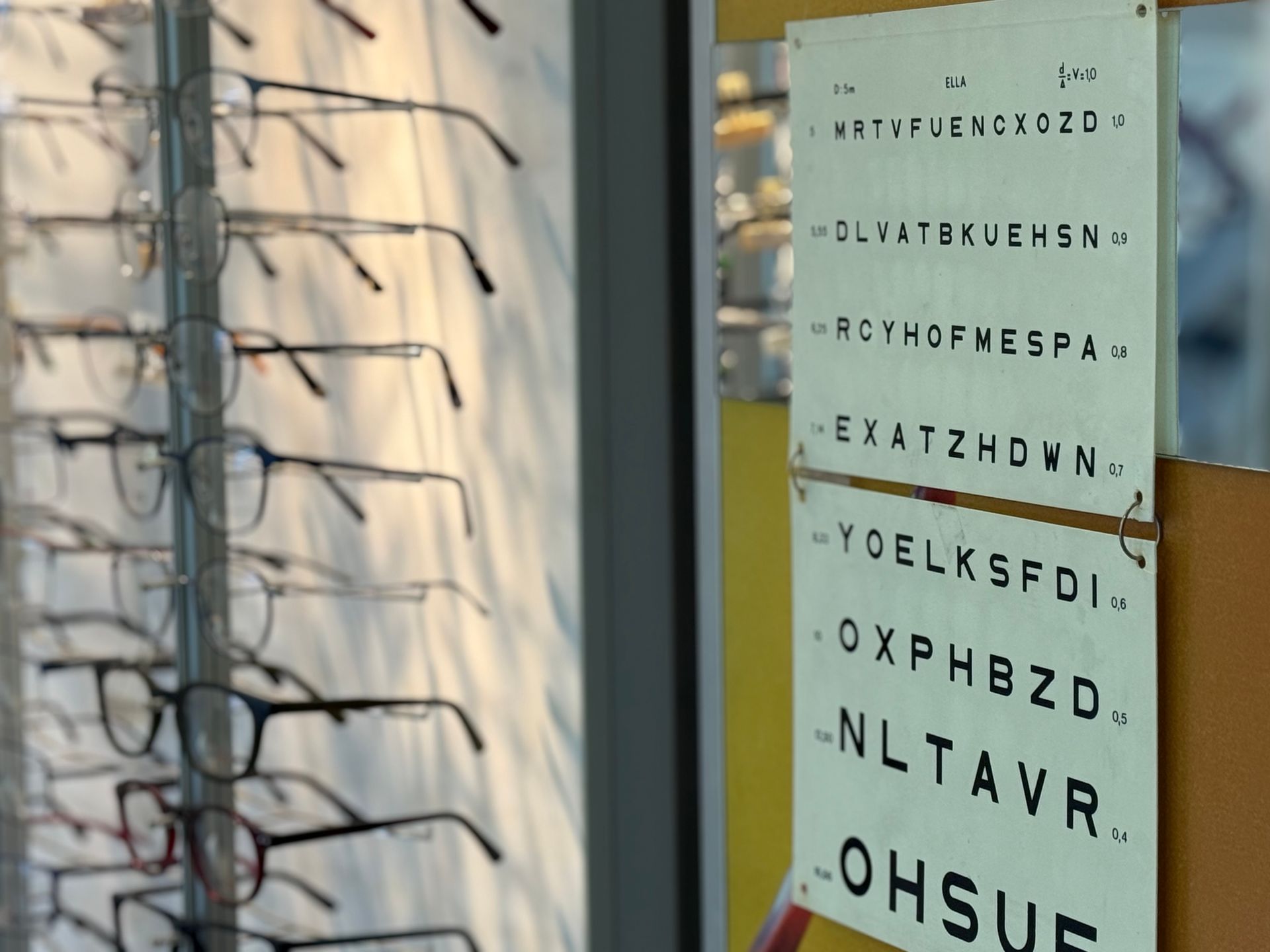 Des lunettes sont exposées à côté d'un tableau optométrique.
