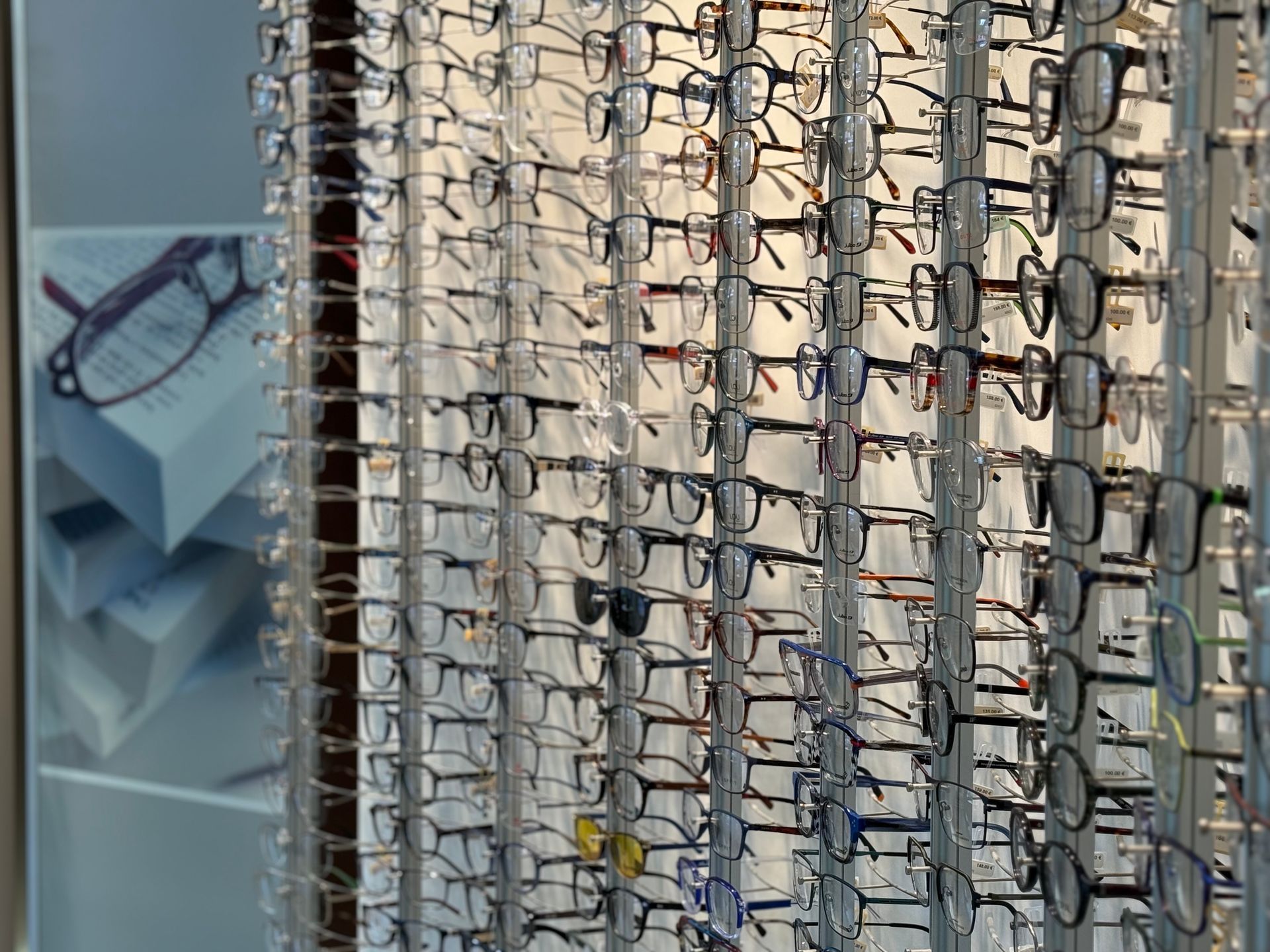 Des rangées de lunettes exposées sur un mur dans un magasin d'optométrie.