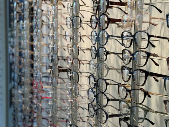 Des rangées de lunettes exposées dans un magasin, de styles et de couleurs variés.