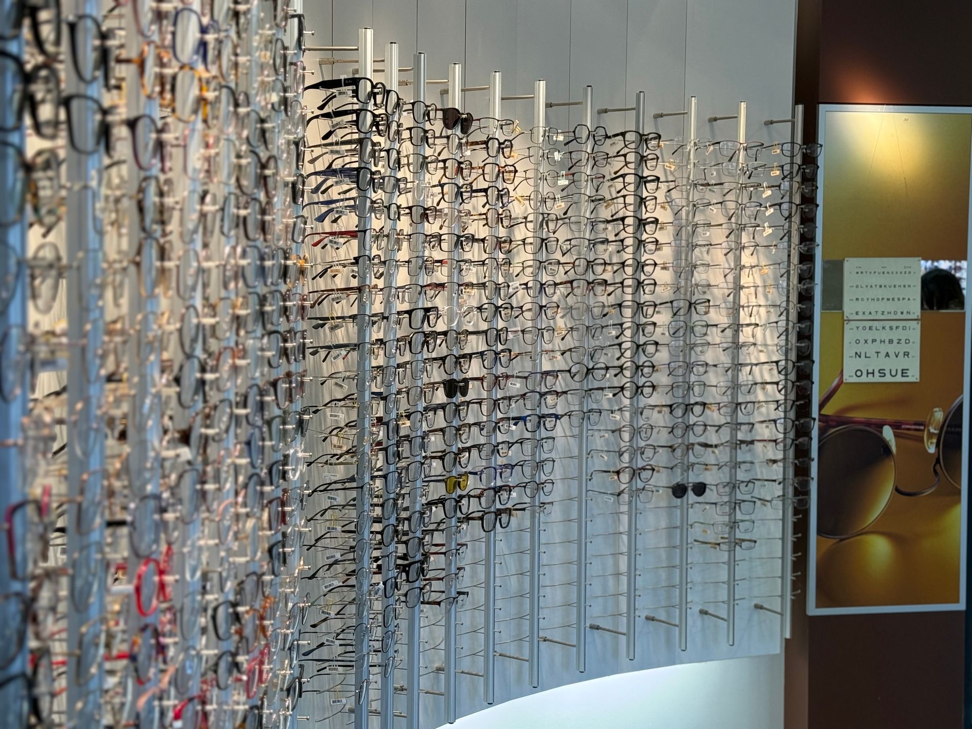 Montures de lunettes exposées sur des présentoirs dans un magasin d'optométrie.