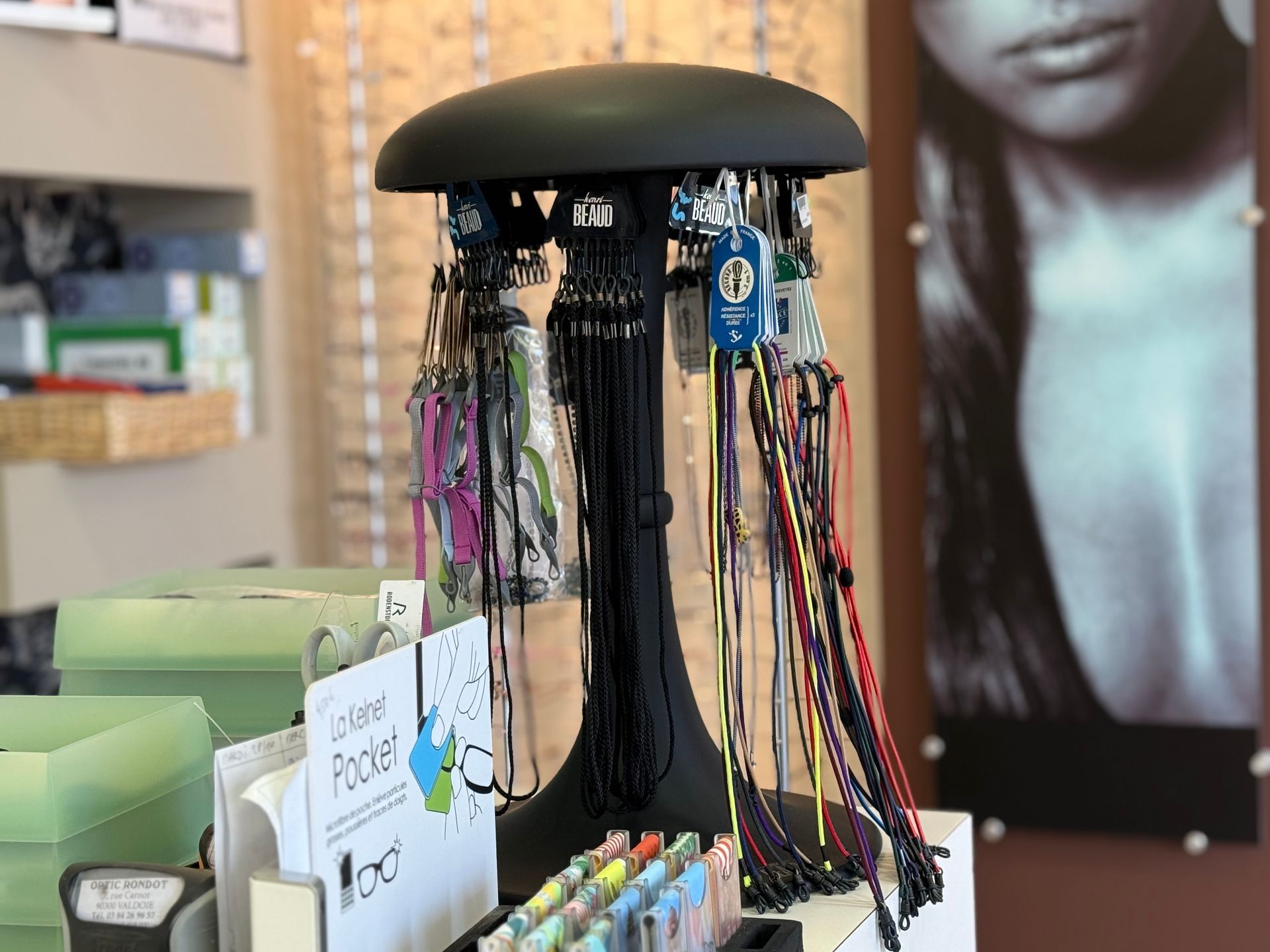 Présentoir d'accessoires pour lunettes dans un magasin d'optique. Support noir avec diverses chaînettes pour lunettes.