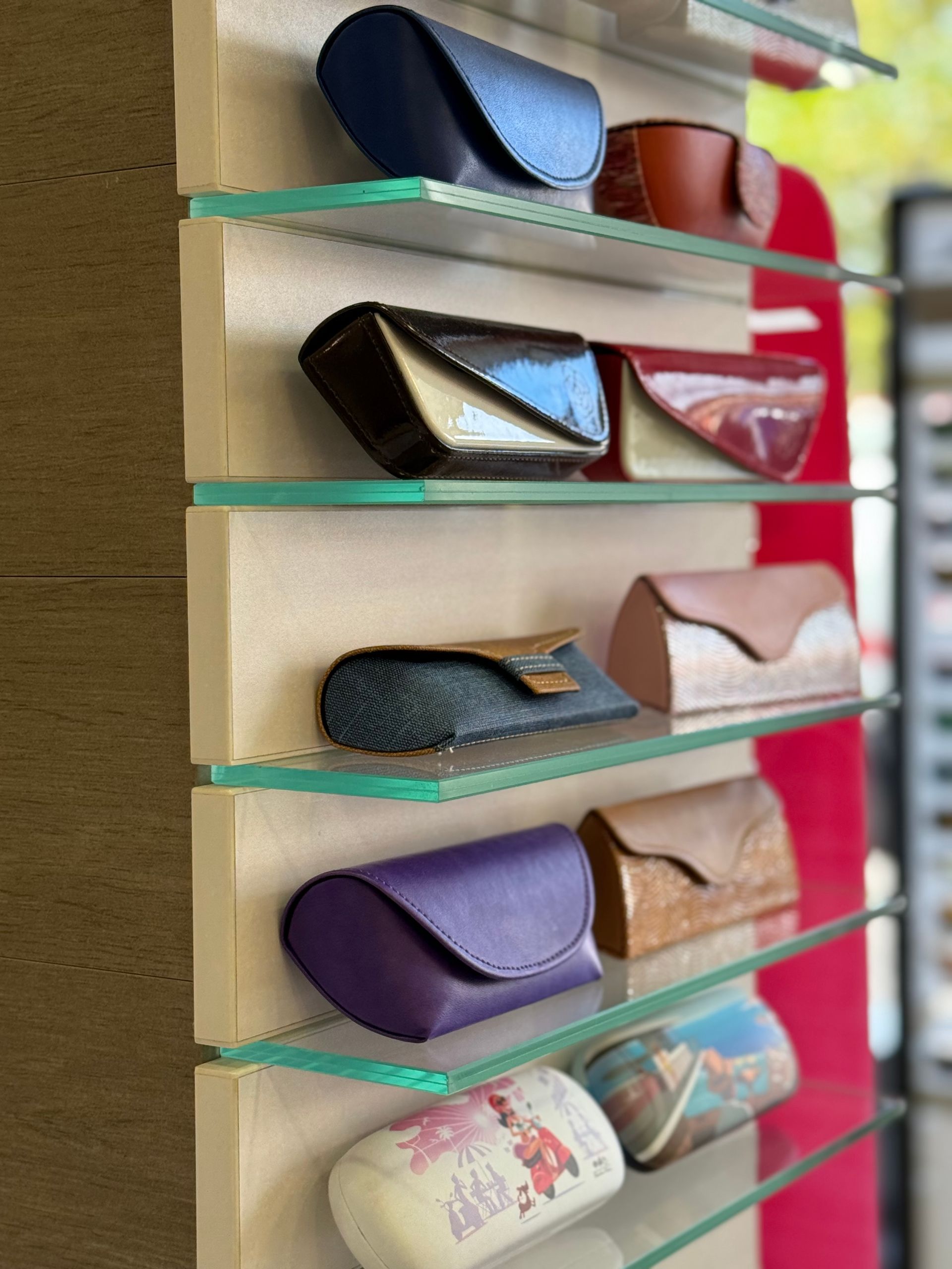 Étuis à lunettes de différentes couleurs sur des étagères d'exposition.