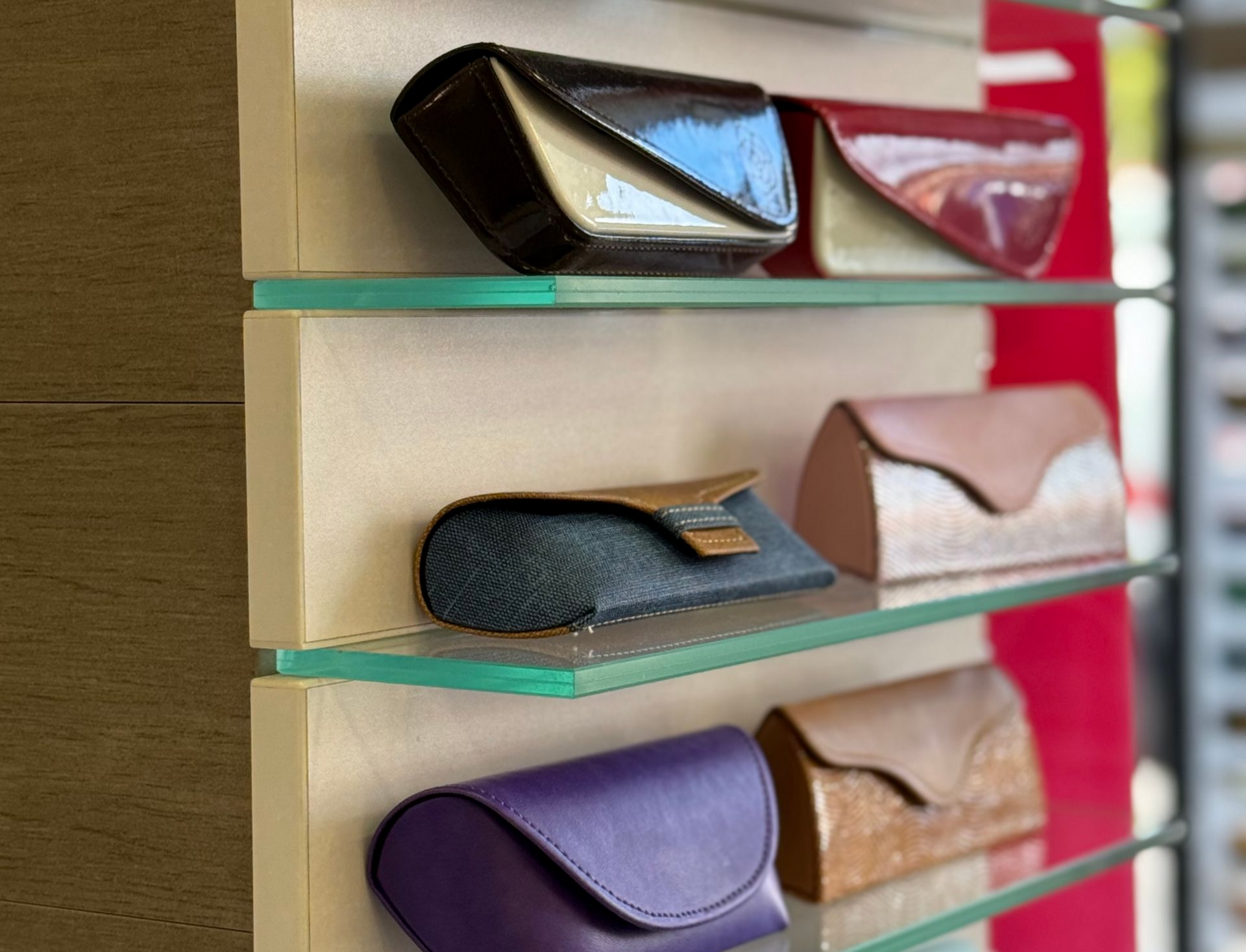 Étuis à lunettes sur étagères, de couleurs et de textures variées.