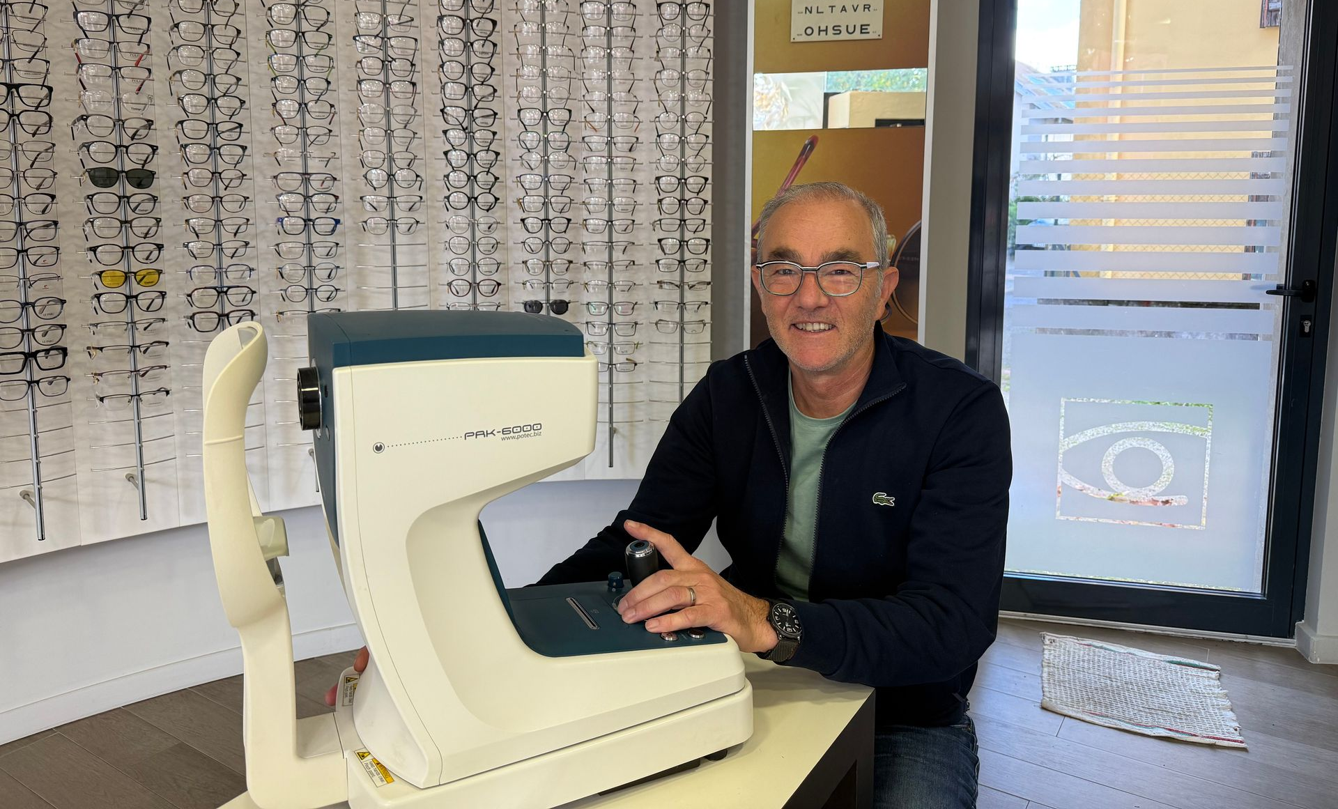M. Rondot dans sa boutique d'optique, devant une machine pour les contrôles de vue.
