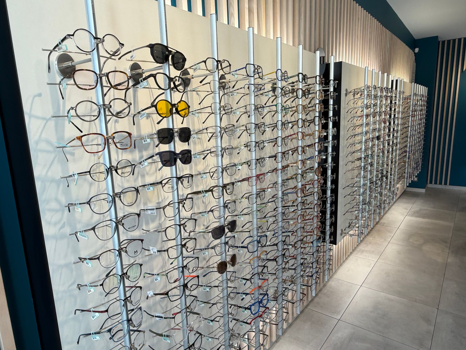 Lunettes exposées sur des présentoirs muraux dans un magasin d'optique.