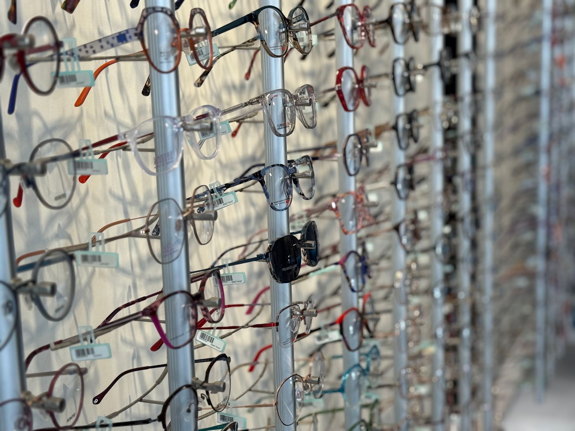 Présentoir mural de lunettes de couleurs et de styles variés.