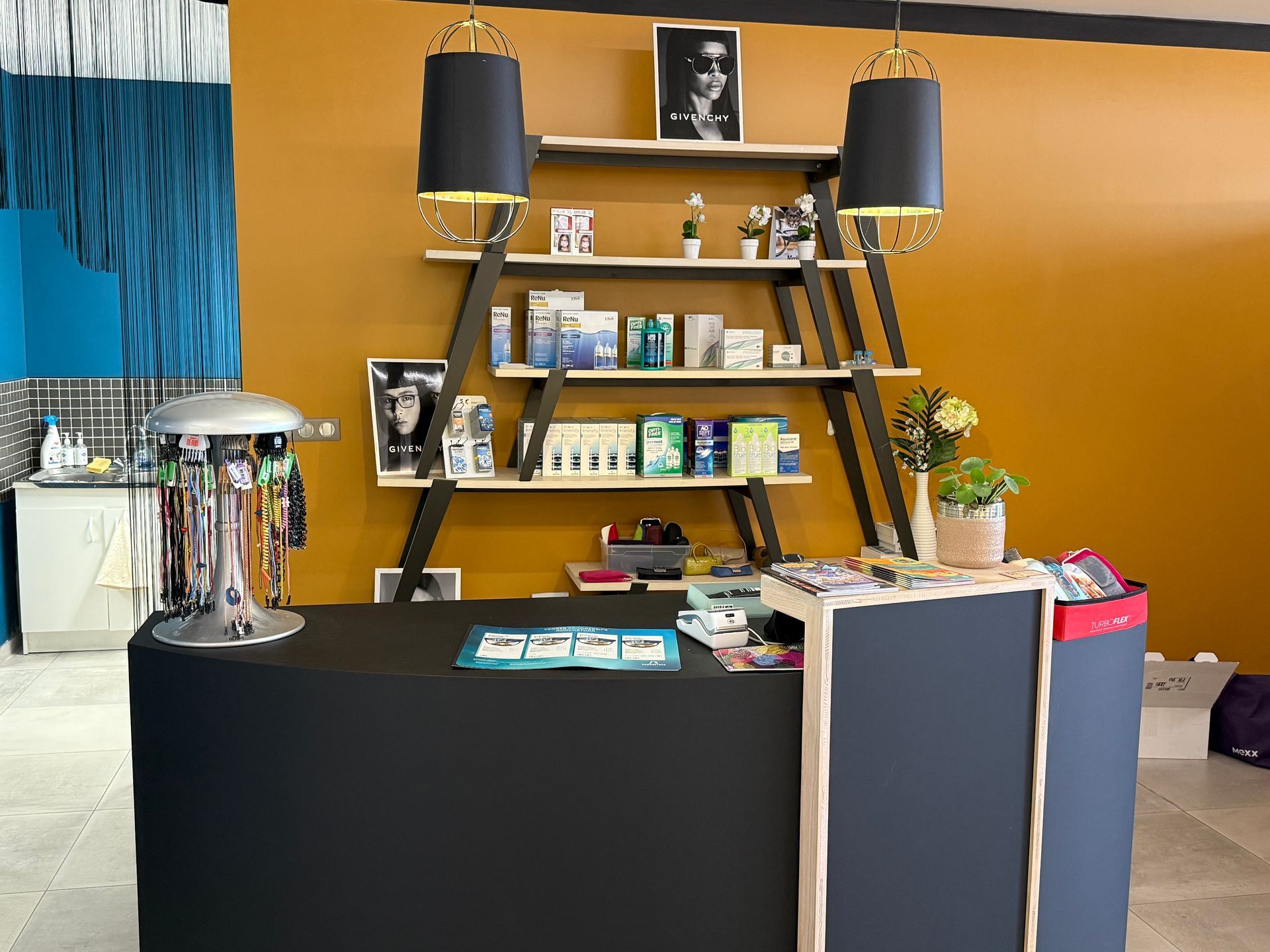 Comptoir de magasin avec surface noire, étagères et produits optiques.