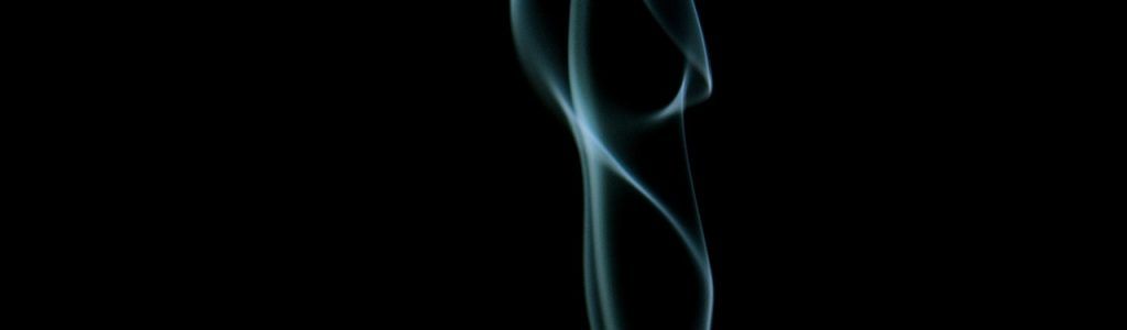 Fumée bleue vaporeuse sur fond noir uni.