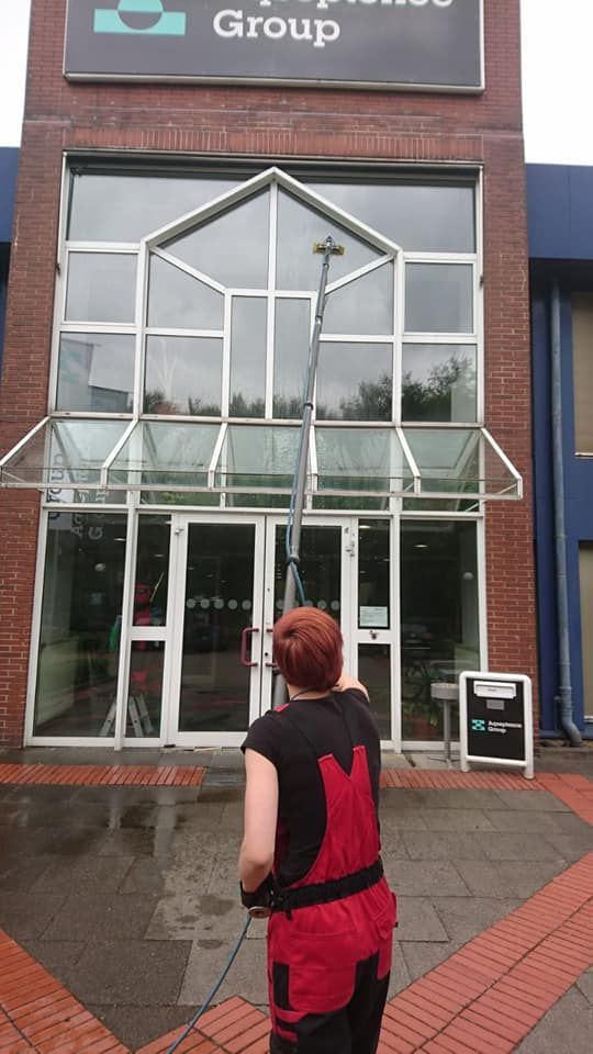 Eine Frau putzt die Fenster eines Gebäudes.