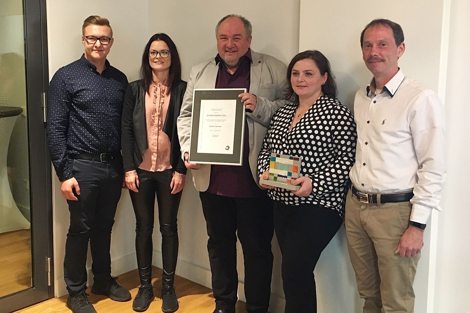 Eine Gruppe von Menschen steht nebeneinander und hält ein Zertifikat in der Hand.