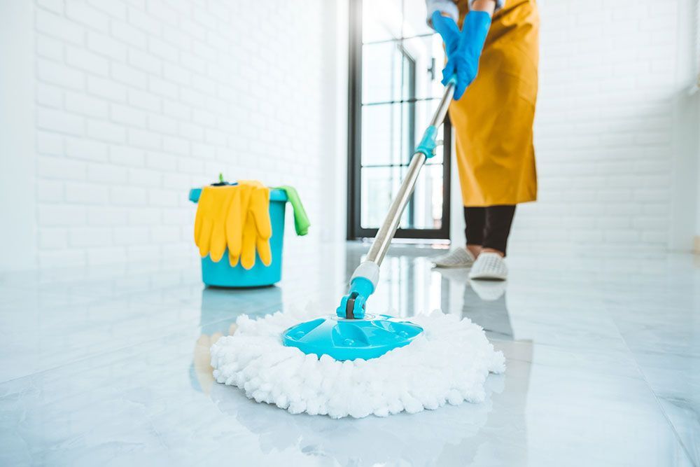 Eine Frau wischt den Boden mit einem Mopp.