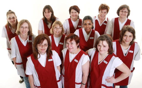 Eine Gruppe von Frauen in roten Schürzen posiert für ein Foto