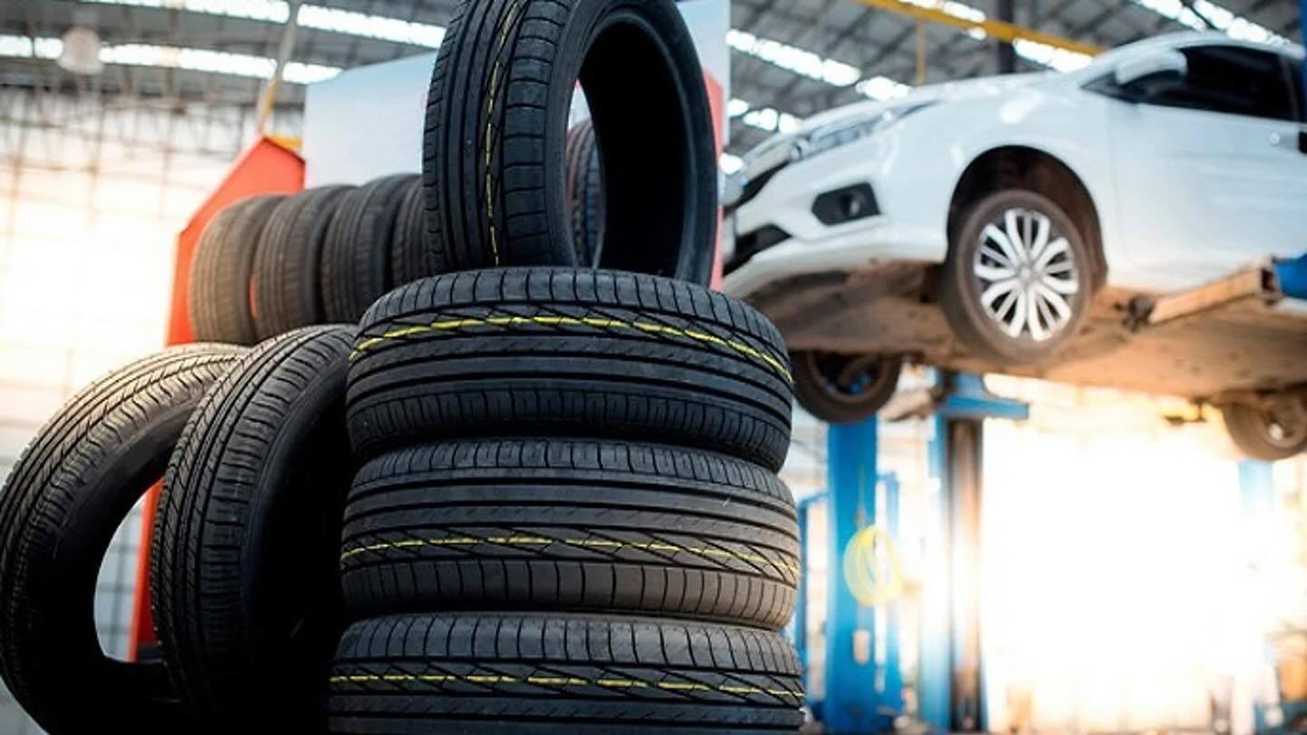 Neumáticos apilados en un taller de reparación con un coche en un elevador.