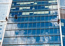 Limpiadores de ventanas en un edificio de gran altura, limpiando el cristal azul reflectante.