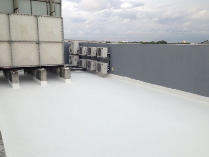 Azotea revestida de blanco con unidades de aire acondicionado y tanque de agua contra una pared gris, bajo un cielo nublado.