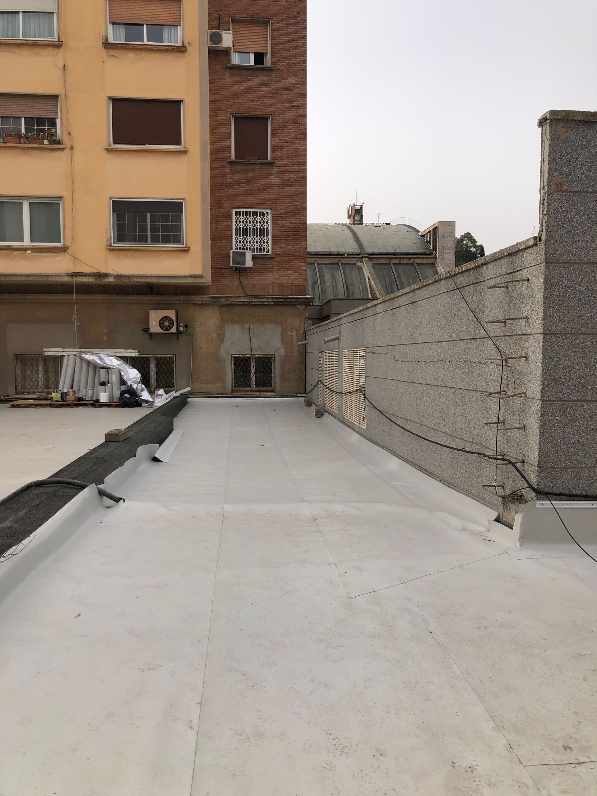 Vista desde la azotea de un edificio y una pared de ladrillos en un día nublado.