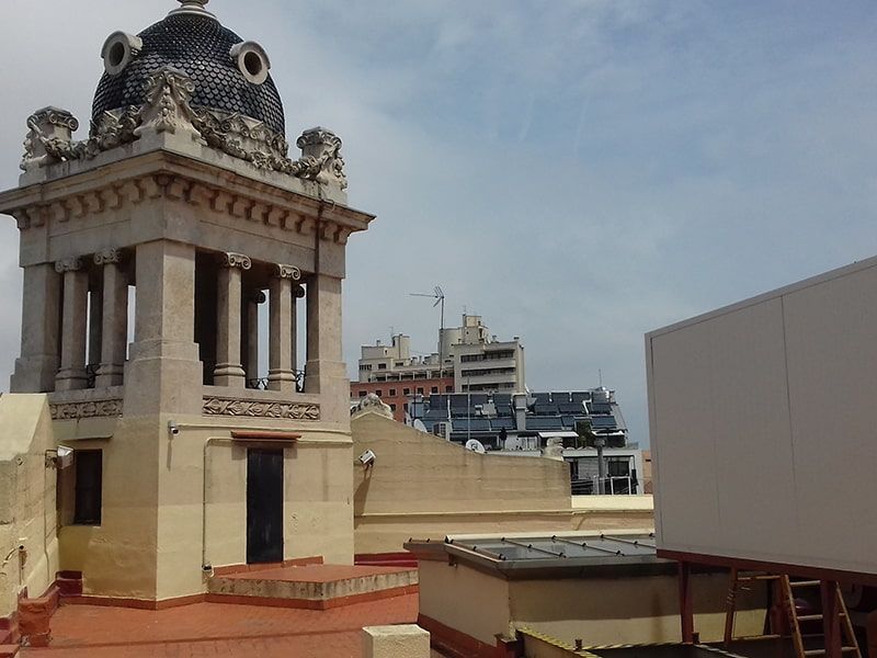 Vista desde la azotea: Torre ornamentada con techo abovedado, edificios de la ciudad bajo un cielo nublado.