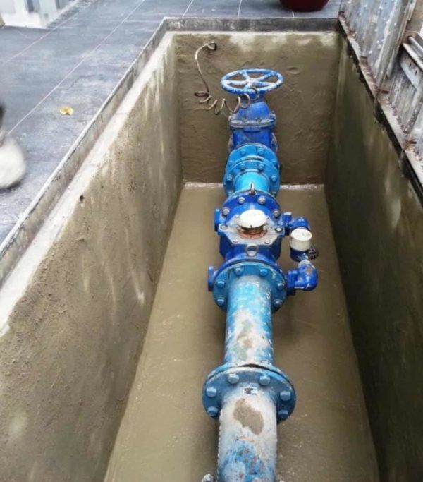 Tuberías y válvulas de agua azules dentro de una bóveda de servicios públicos de hormigón.