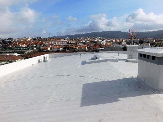 Techo comercial blanco con vista a una ciudad bajo un cielo azul.