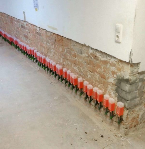 Fila de tapones rojos y tubos verdes instalados a lo largo de una pared de ladrillo y hormigón.