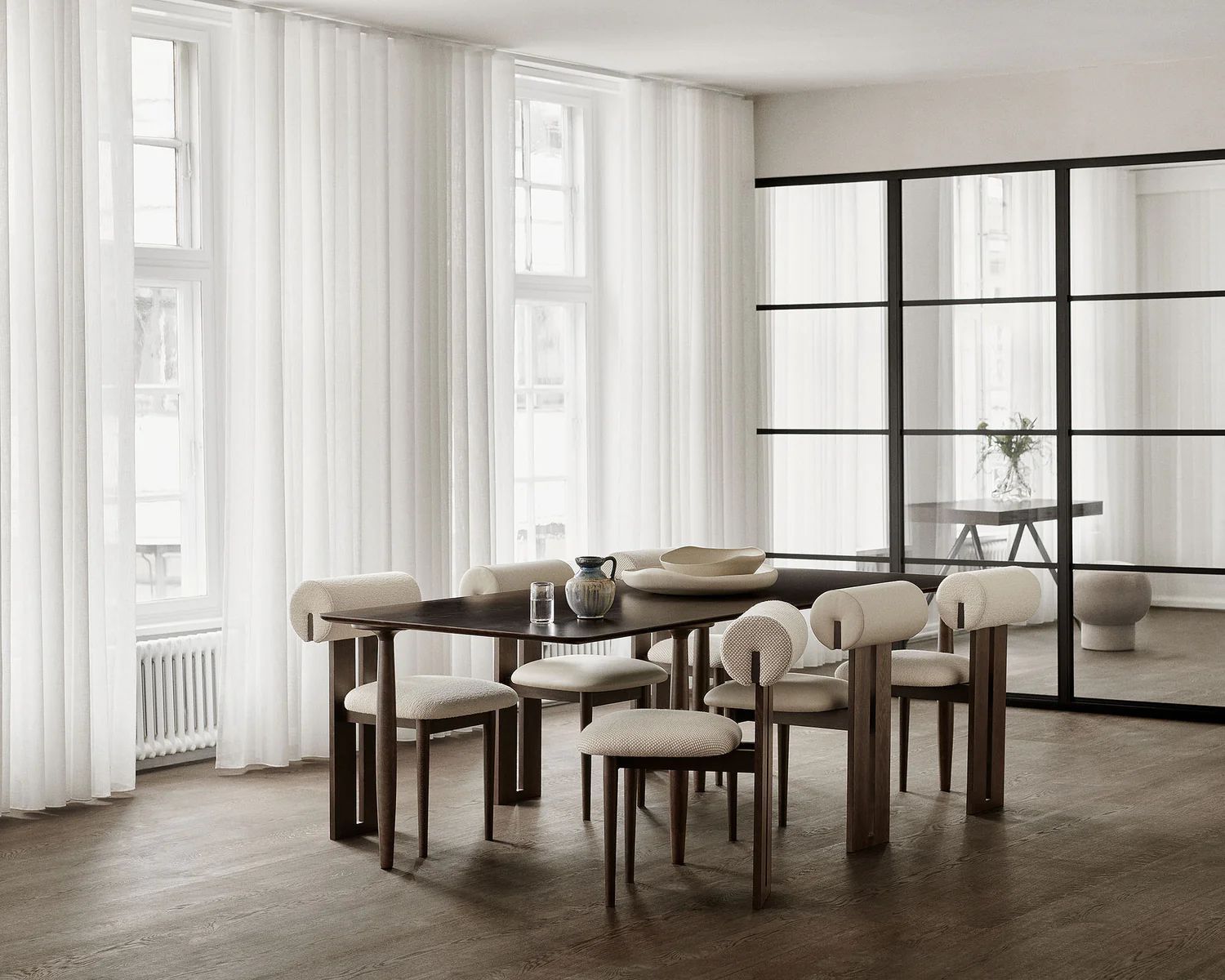 Bureau moderne avec un long bureau, une chaise rouge, un ordinateur portable, des livres et une grande fenêtre donnant sur la ville.