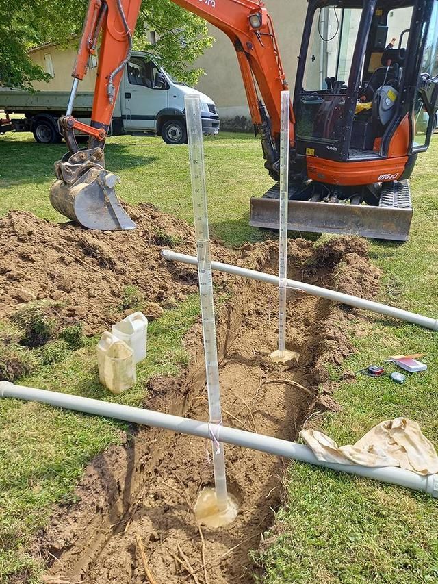 Un poteau en bois placé dans un trou avec une tranchée, dans un champ herbeux, en préparation d'une clôture.