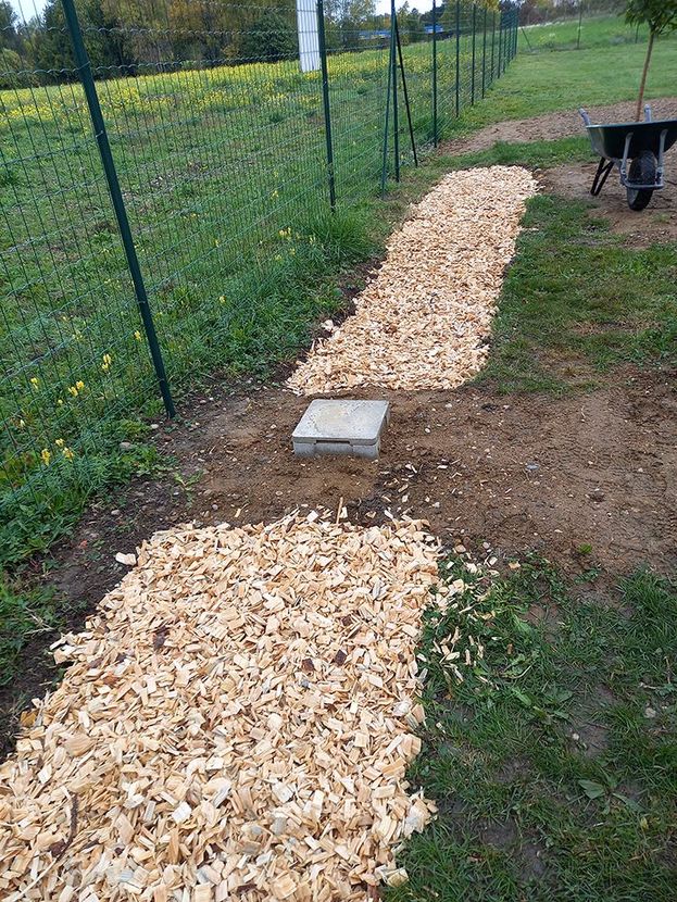 Champ d'épuration rempli de gravier avec tuyaux de drainage bleus, revêtements noirs et ports d'accès, construit dans une zone creusée.