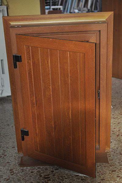 Un armario de madera con la puerta abierta está sobre un suelo de baldosas.