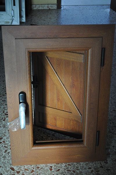 Una puerta de madera con tirador reposa sobre un suelo de baldosas.